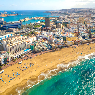 Playa de Las Canteras in Las Palmas op Gran Canaria met een breed zandstrand, helderblauw zeewater en gebouwen langs de boulevard.